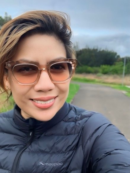 Eleonor Collins outdoors, smiling, wearing sunglasses and a dark puffer jacket.